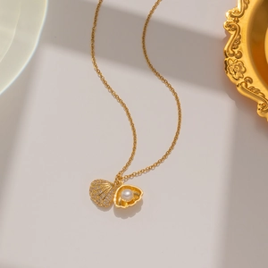 Macro detail of gold shell pendant necklace with sparkling zircons and a white pearl