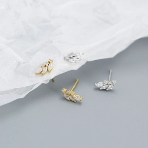 Detail showing elegant gold and silver leaf earrings with marquise-cut zircon stones