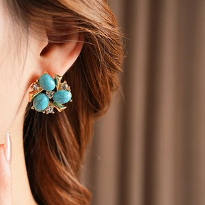 Gros plan sur boucle d'oreille fleur vintage dorée avec pierres turquoises et strass
