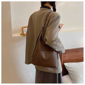Modèle portant un grand sac cabas vintage marron sur l'épaule dans une pièce minimaliste