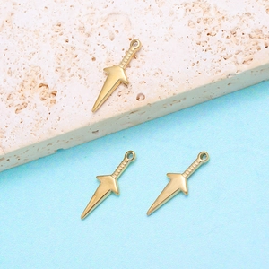 Macro detail of three golden stainless steel dagger pendants on a stone surface