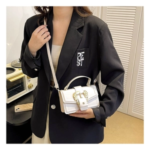 Close-up of a white leather mini square bag featuring a gold horseshoe metal buckle