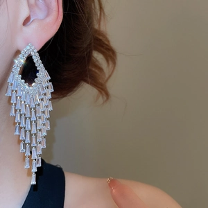 Close-up of sparkling zircon geometric tassel earrings worn by a model in silver finish