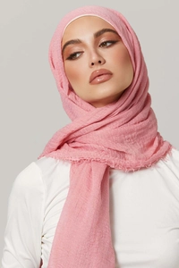 Detailed texture of pink pleated cotton viscose hijab with frayed edges on model