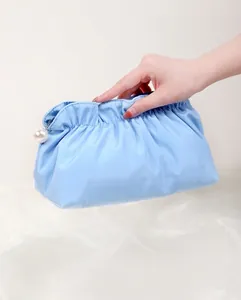 Dettaglio della borsa da trucco plissettata azzurra con cerniera a forma di perla bianca