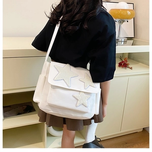 Rear view of model wearing a white crossbody bag featuring white plush star decorations