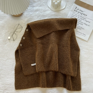 Detail of brown ribbed knit shawl featuring three buttons and brand label on fabric