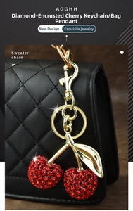 Detail of red rhinestone cherry keychain with gold leaves on a black quilted bag