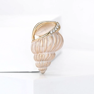 Detailed view of conch brooch with pink enamel and crystals on geometric stand