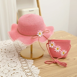 Close-up of pink straw hat and mini bag set with daisy flower and bow details