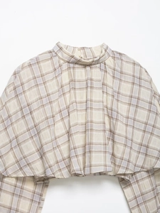 Macro shot of plaid crop top featuring high collar, pleated chest, and back buttons