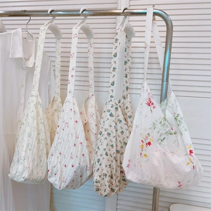 Detail of four floral cotton lace tote bags hanging on a rack with delicate embroidery