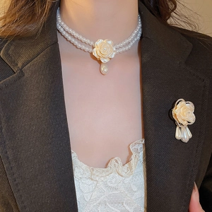 Détail d'un ensemble de collier et broche en perles avec rose blanche et cristaux