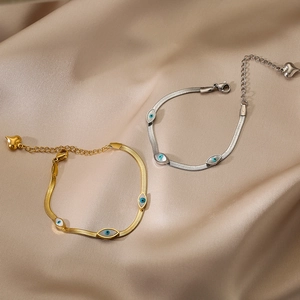 Gold and silver snake chain bracelets with evil eye charms and heart pendants on silk