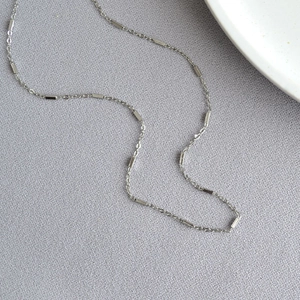 Detail of silver minimalist necklace featuring rectangular bars on a thin cable chain
