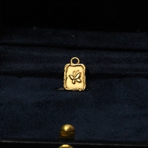 Detailed close-up of a gold butterfly pendant with engraved texture on velvet