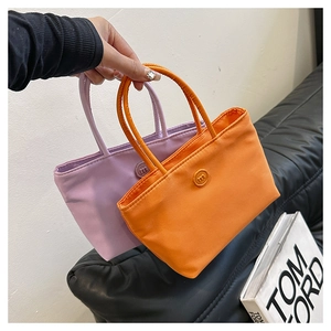 Sacs seaux à la mode en nylon violet et orange avec boucle en M sur un canapé noir