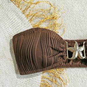 Detail of brown pleated bikini top featuring a golden starfish buckle with straw hat background