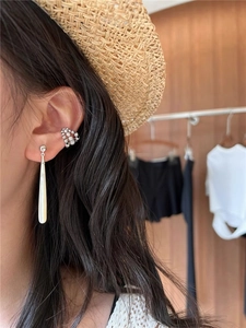 Detail of teardrop white mother-of-pearl earrings and silver zircon double ear cuff