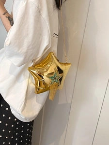 Detail of star-shaped crossbody bag featuring golden tassels and emerald rhinestones
