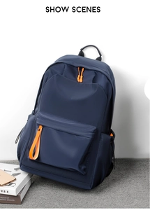 Detail view of water-resistant oxford backpack featuring orange zipper pulls and side pockets