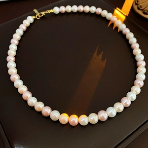 Close-up of elegant pearl necklace with white and pink pearls on leather surface