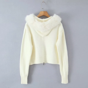 Close-up of a white knitted cardigan featuring a luxury faux fur collar and metal zipper