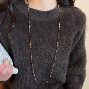 Close-up of brown tiger eye beaded necklace on dark sweater showing natural stone textures
