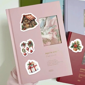 Detailed Christmas stickers with snow cottages and gift boxes applied on a pink book cover