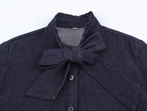 Close-up of dark blue denim shirt with a large bow collar and metallic button detailing
