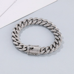 Detailed view of silver Cuban link bracelet with full diamond inlay on textured gray surface