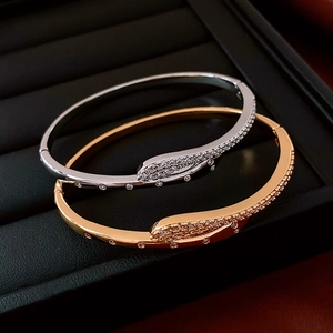 Close-up of snake-shaped gold plated bangles with inlaid zircons and spring clasps