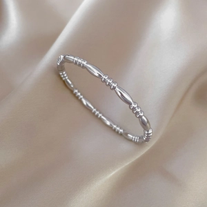Detailed top view of silver beaded stainless steel bracelet on elegant silk fabric