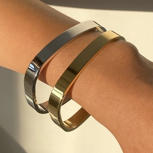 Polished gold and silver stainless steel open bangle set worn on a model wrist