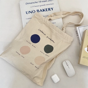 Detail of canvas tote bag with color palette print next to books and wireless earphones
