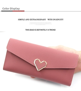 Detail der herzförmigen Goldschnalle an der rosa Langbörse aus genarbtem Leder