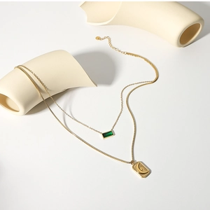Close-up of gold double-layer necklace with green gemstone and moon star square charms