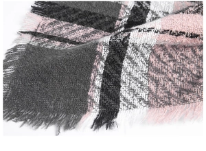 Detail van roze en grijs geruit bouclé breisel met natuurlijke franje versieringen