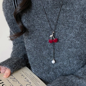 Detail of red flocked cherry pendant with white pearl on a black minimalist necklace