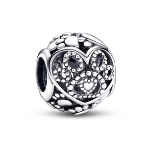 Detailed view of a silver hollow heart charm with intricate beadwork and circular patterns