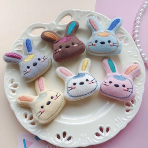 Overhead view of six colorful embroidered bunny patches on a white ceramic tray