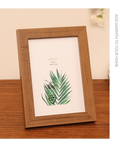 Close-up of minimalist wood grain photo frame on tabletop with warm home decor setting
