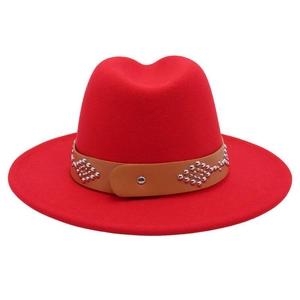 Detail of red wool felt fedora featuring a brown leather band with silver metal studs
