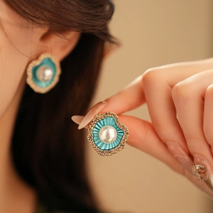 Gros plan d'un modèle portant des boucles d'oreilles coquillage en émail bleu et perle