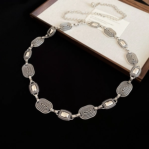Detail of vintage silver oval embossed metal link chain belt on a black background