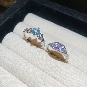 Macro detail of silver rings featuring a blue gemstone and sparkling zircon pave accents