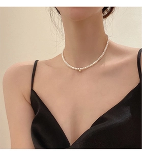 Elegant natural pearl necklace with gold bead accents on model's neck collarbone