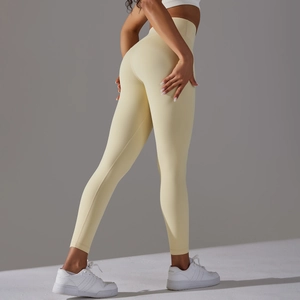 Detail view of high-waist cream yellow yoga pants showing booty lifting seams and stretch fabric