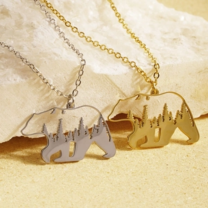 Detailed view of hollow bear pendant necklaces with forest landscape in gold and silver