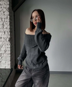 Close-up of a charcoal grey off-shoulder knit sweater with ribbed texture and denim